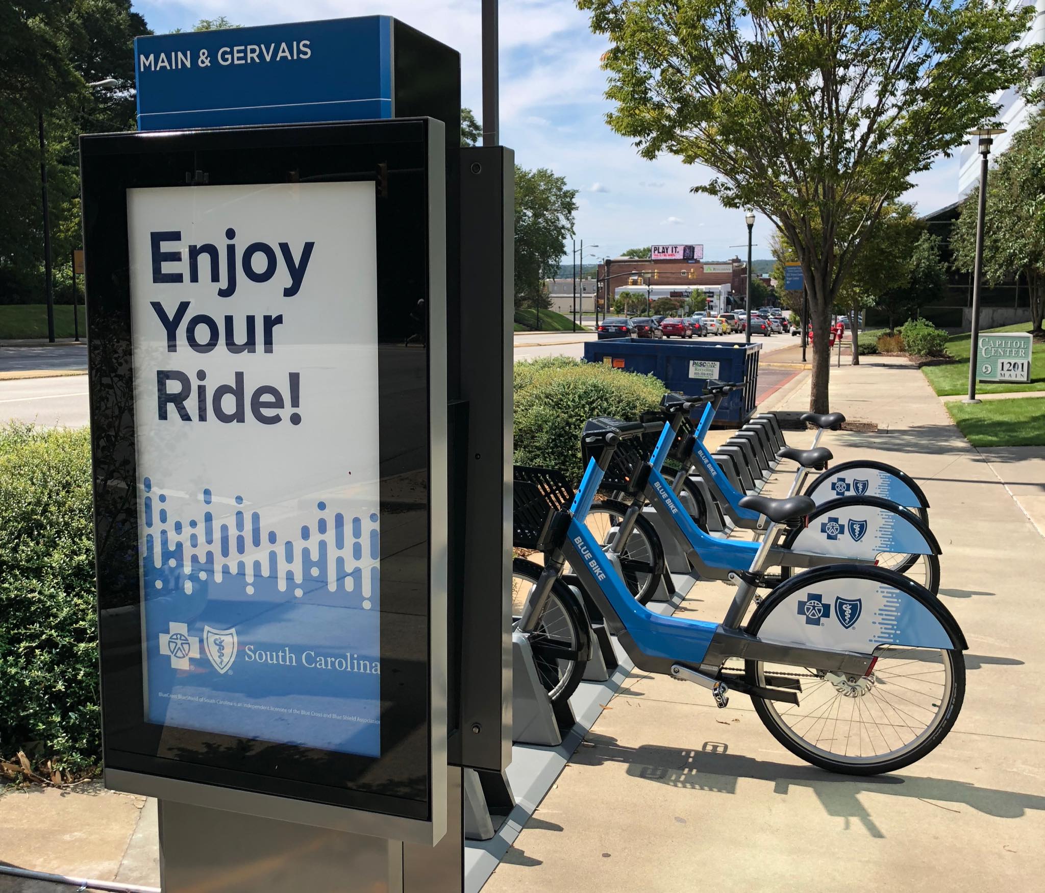 Blue Bikes docked at a station next to a sign that says Enjoy your ride!